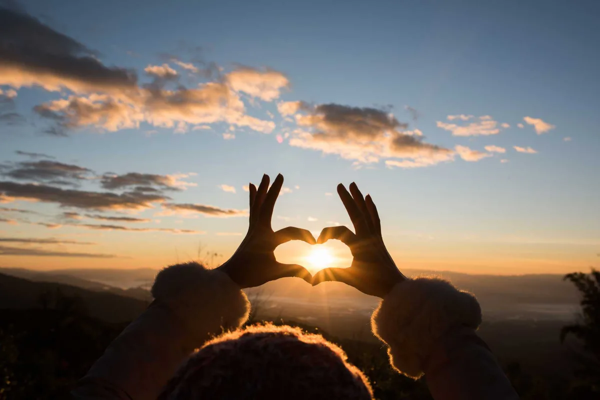 Hände formen bei Sonnenuntergang ein Herz